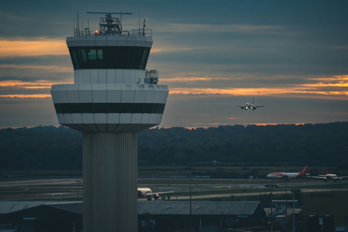 Control tower at sunset with aircraft on approach